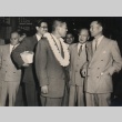 Hayato Ikeda wearing lei, speaking with several men (ddr-njpa-4-151)