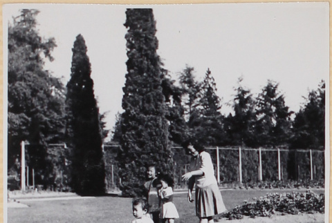 Woman with three children playing on lawn (ddr-densho-522-13)