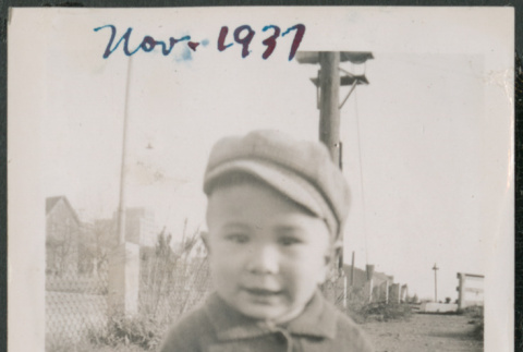 Photo of a toddler in a jacket and hat squatting (ddr-densho-483-704)