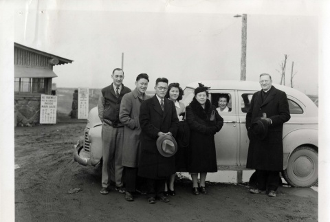 Rev. L. H. Tibesar posing with the Kinoshita family at gates of Camp Minidoka, Idaho (ddr-densho-403-8)