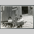 Photograph of Ned and Harry Morioka with two other children posing in front of the infirmary at Cow Creek Camp in Death Valley (ddr-csujad-47-137)