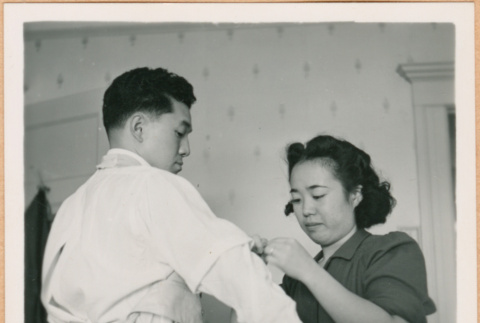Woman helping Henri Takahashi adjust his sleeve (ddr-densho-410-457)