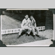 Two men sitting on low bench outside camp building.  Joe Iwataki on left (ddr-ajah-2-477)