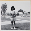 Girl standing on lawn holding dog (ddr-densho-522-116)