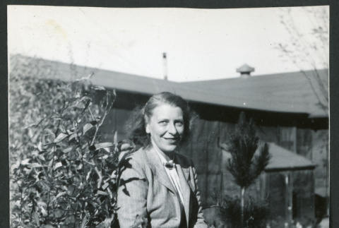 Photograph of Dr. Agnes V. Barlett sitting on a rock in front of the Manzanar hospital (ddr-csujad-47-319)