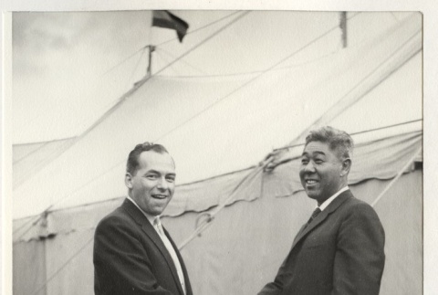 Two men shaking hands in front of the convention tent (ddr-jamsj-1-513)