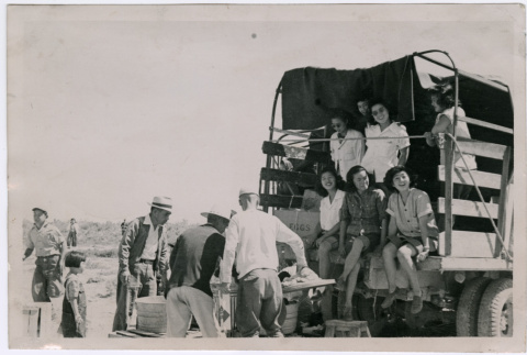 Group of women in back of truck  with other agricultural workers (ddr-densho-560-26)