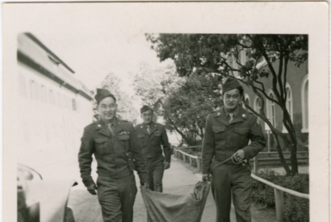 Three men in uniform carrying large sack (ddr-densho-458-34)
