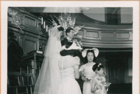 Henri Takahashi and Tomoye (Nozawa) Takahashi standing at altar with bridal party (ddr-densho-410-480)