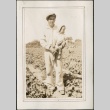 A man holding a baby in a farm field (ddr-densho-316-50)