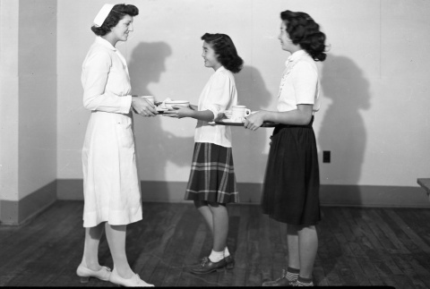 Two women handing a nurse trays of food (ddr-fom-1-637)
