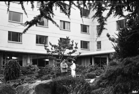 Two people talking in courtyard of Xavier Hall, Seattle University (ddr-densho-354-2065)