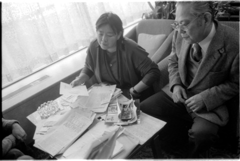 Loni Ding, Barry Saiki and one other looking through clippings (ddr-densho-1007-1171)