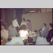 Tomoye Takahashi standing in front of group seated at tables (ddr-densho-426-612)