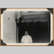 Gary Kikawa posing below a prescriptions sign (ddr-densho-542-164)