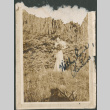 Woman with bouquet of flowers standing in field. (ddr-densho-316-167)