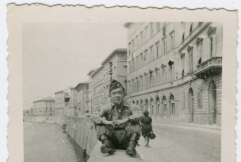 Soldier sitting on wall near water in Italy (ddr-densho-368-74)