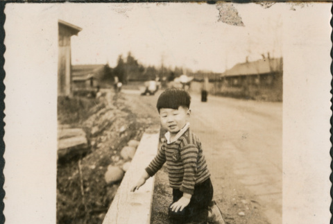 Jon David Sakura kneeling by side of road (ddr-densho-523-84)