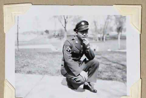 Man in military uniform kneels on a sidewalk (ddr-densho-404-386)