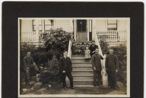 Family standing and sitting on porch steps outside house (ddr-densho-329-595)