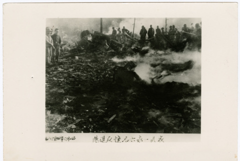 Men stand around the smoking remnants of a house (ddr-densho-381-65)