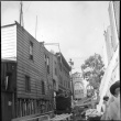 Men working in narrow street with lumber and equipment (ddr-densho-426-2155)