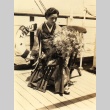 Woman seated holding flower bouquet on Tatsuta Maru deck (ddr-njpa-4-29)