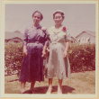 Two women standing by hedge wearing corsages (ddr-densho-522-48)