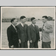 Four men in suits with barracks in background (ddr-densho-523-141)