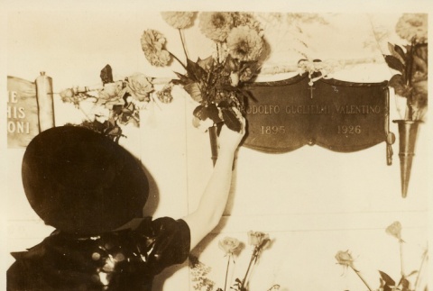 A woman placing flowers on Rudolph Valentino's grave (ddr-njpa-1-2287)