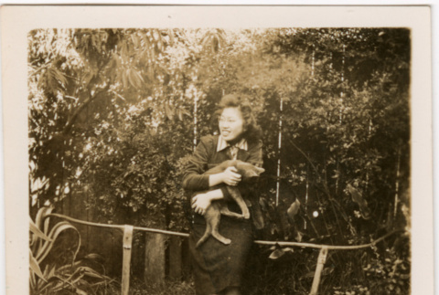 Tomoye (Nozawa) Takahashi holding cat in garden (ddr-densho-426-2120)