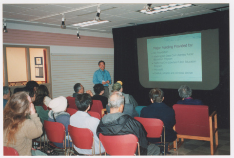 Tom Ikeda giving presentation with projection screen of donors (ddr-densho-506-7)
