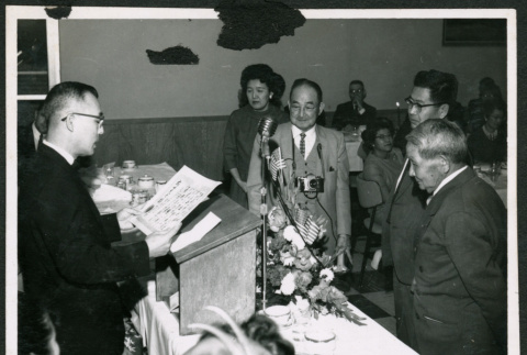 Man at podium reading a document (ddr-densho-293-173)