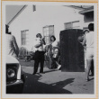 Man holding baby, two men playing basketball (ddr-densho-522-88)