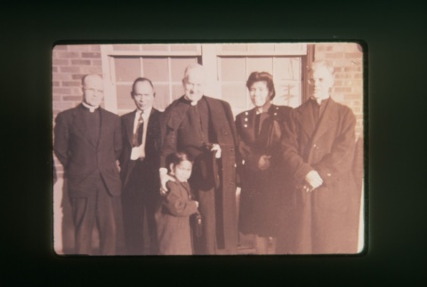 (Slide) - Image of three priests, man, woman and child outside Maryknoll (ddr-densho-330-152-master-2ee582fbb3)