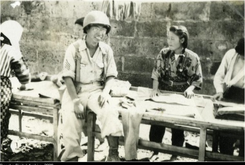 Nisei soldier with Okinawan women doing laundry (ddr-densho-179-145)
