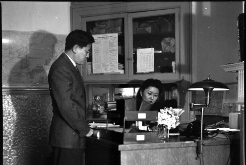 Man standing next to desk, woman seated at desk (ddr-densho-426-951)