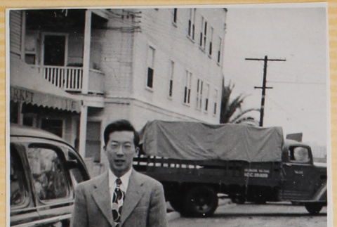 Man standing next to car on street (ddr-densho-522-2)