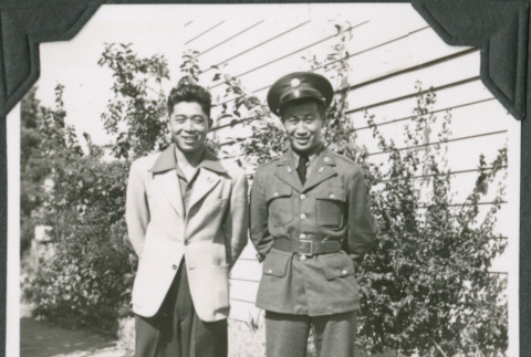 Man in uniform and man in civilian clothes standing outside building (ddr-ajah-2-148)