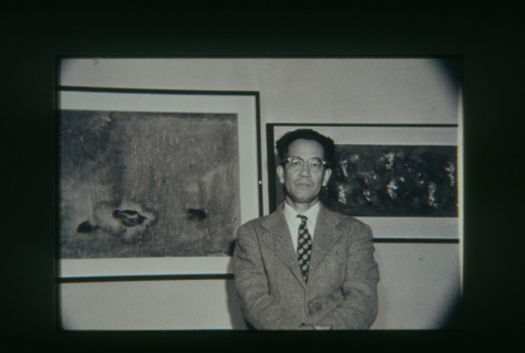 (Slide) - Image of man standing in front of two framed paintings (ddr-densho-330-154-master-99ed6a7582)