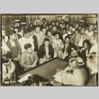 People gathered around a man sitting at his desk (ddr-njpa-13-1441)