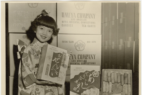 Young girl in kimono posing with Umeya products (ddr-densho-499-178)