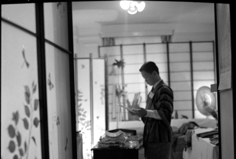 Man standing by table surrounded by shoji screens (ddr-densho-426-2474)