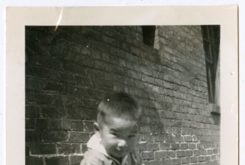 Photo of a child sitting on a ledge with a drum (ddr-densho-483-744)