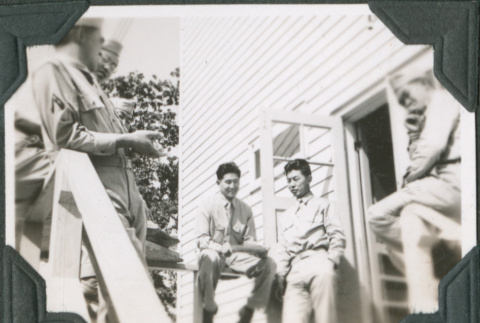Group of men sitting on railing outside building (ddr-ajah-2-399)