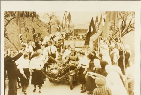 Civilians waving and saluting as a Nazi motorcade passes by (ddr-njpa-13-894)