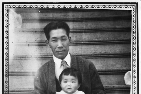 Man sitting on steps holding baby (ddr-ajah-6-672)