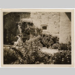 Tomoye (Nozawa) Takahashi sitting in garden by stone building (ddr-densho-426-1785)