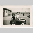 Two children in toy car with barracks in background (ddr-densho-329-1358)