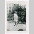 Photo of a child walking down a sidewalk near a fence (ddr-densho-483-738)